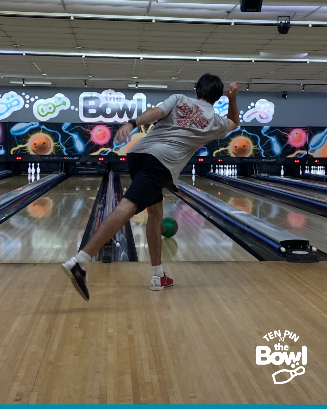 A boy mid-throw sending a bowling ball down the lane, with The Bowl sign behind him