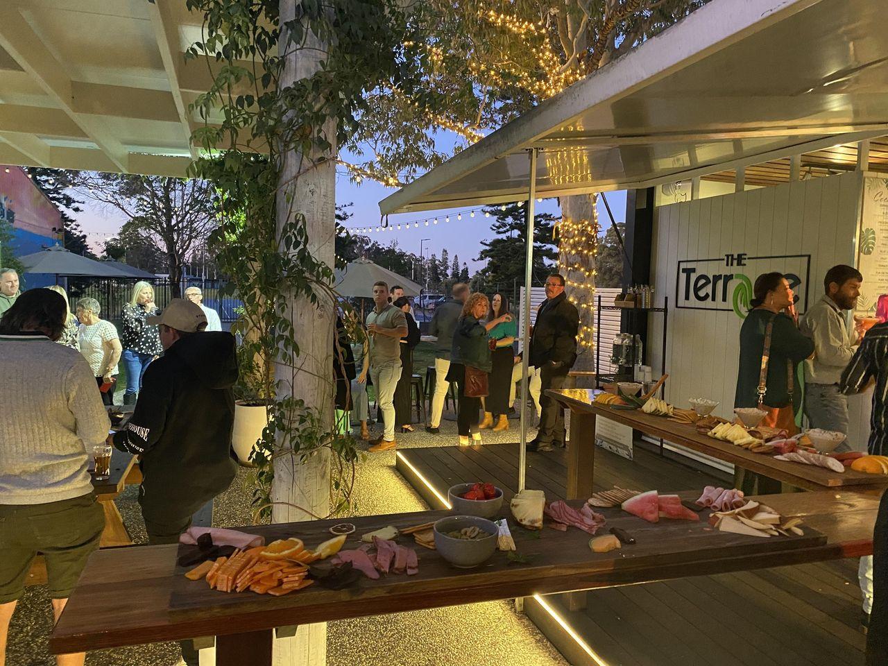 Guests gathering at the grazing table on The Terrace at The Bowl Port Macquarie at sunset, with fairy lights coming on